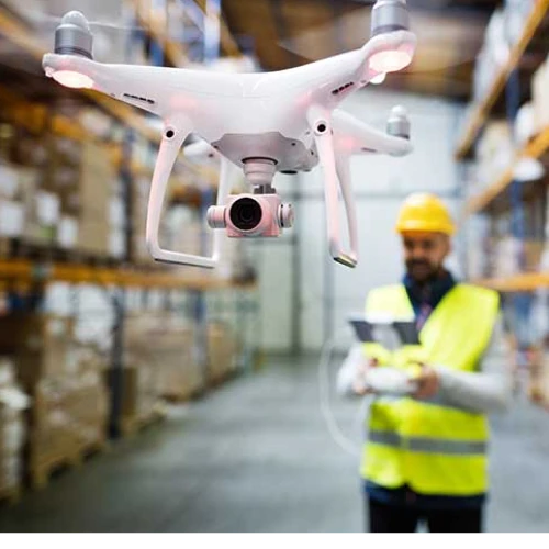 Un ouvrier du bâtiment conduit un drone dans un entrepôt avec sa manette de commande